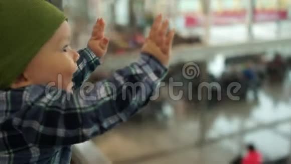 一岁的孩子用钢笔敲玻璃看着机场候车室父亲抚养孩子视频的预览图