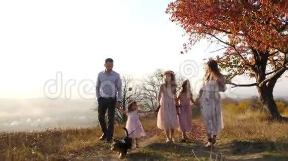 快乐的年轻豪华打扮的一家人和他们的狗在秋天公园散步视频的预览图