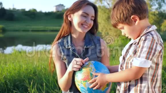 梦想的旅行微笑的孩子与全球看世界坐在绿色的草坪上视频的预览图