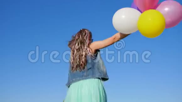 时髦的女孩手里拿着彩色的头发和气球在天空中跳跃视频的预览图