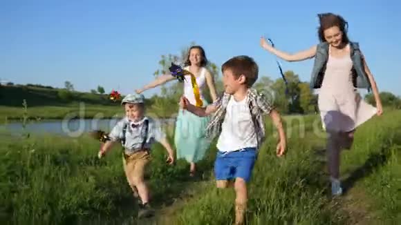 快乐的孩子们和玩具风车一起欢笑穿过草地视频的预览图