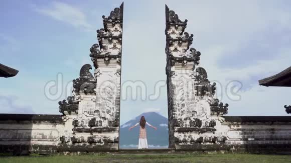 女人张开双臂站在寺庙门口看着阿贡火山视频的预览图