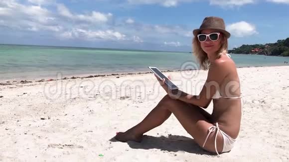 那个年轻的女人拿着一块药片坐在海滩上视频的预览图