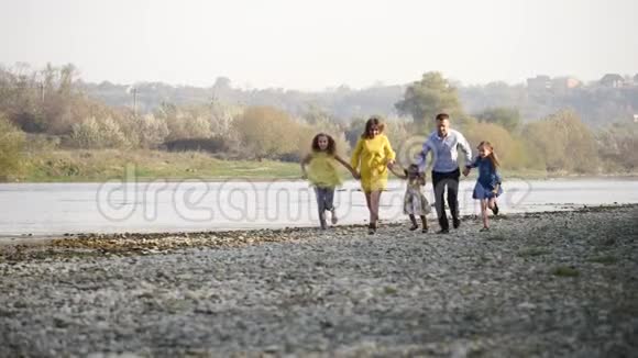 幸福的年轻家庭在河边奔跑视频的预览图