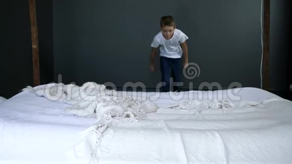 娱乐快乐的男孩在卧室里慢动作地在床上奔跑视频的预览图