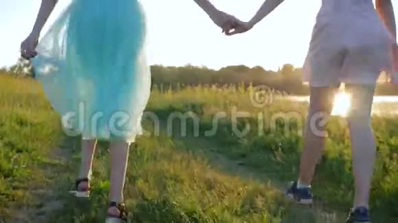 快乐的女孩留着长长的头发的十几岁的孩子沿着湖边的草地牵着手视频的预览图