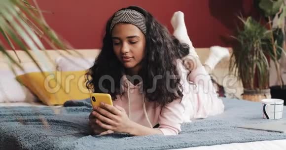 早上躺在床上使用智能手机的年轻女子视频的预览图
