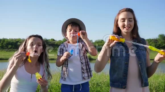 快乐的一家人在夏天的背景天堂河附近吹肥皂泡视频的预览图
