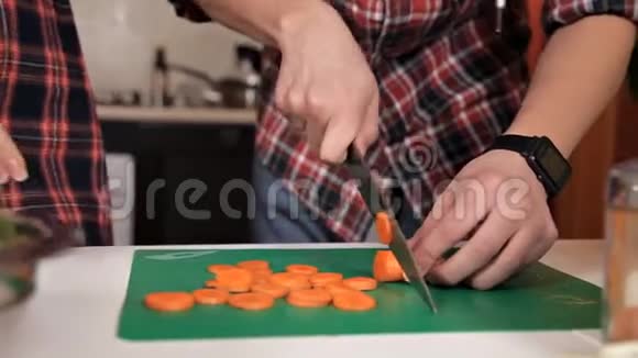 年轻夫妇做饭男人和女人在家里切胡萝卜做沙拉视频的预览图
