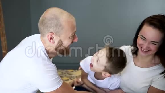 快乐的父母和儿子一起在卧室的家中的床上度过快乐的时光视频的预览图