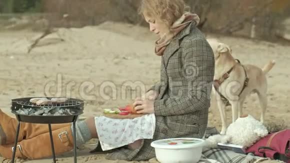 母亲带着女儿一个穿着外套的年轻女人坐在河边的海滩上大海野餐做饭做饭视频的预览图