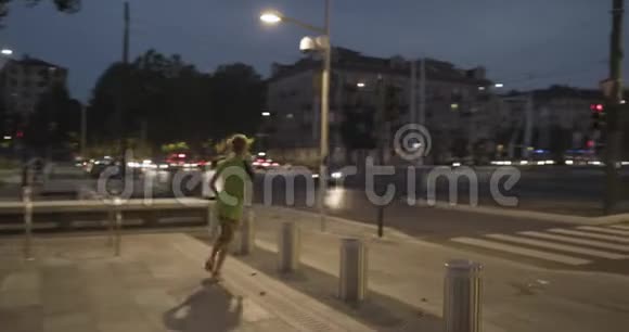 穿着健身服的女士在斑马线附近停止跑步回到下面的视图夏天的晚上或晚上工业绿色城市视频的预览图