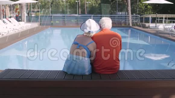 幸福成熟的夫妻坐在池边可爱的高级男女在酒店综合体放松快乐视频的预览图