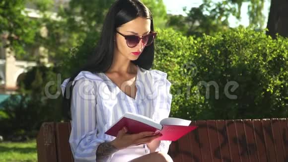 戴太阳镜的漂亮女人读完了公园里的书视频的预览图