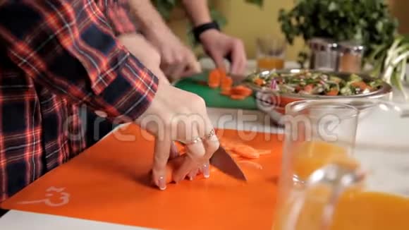 年轻夫妇做饭男人和女人在家里切胡萝卜做沙拉视频的预览图