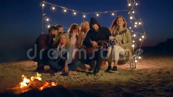 青春的生活欢乐的男女用火弹吉他享受海边的休息视频的预览图