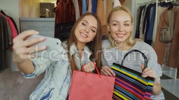 两位年轻女性在服装店购物后用智能手机自拍的特写镜头一开始他们摆姿势视频的预览图