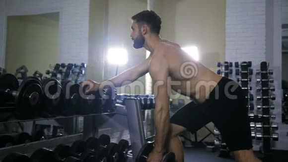 一个运动健将在健身房锻炼手臂肌肉在镜子旁边的一个架子上锻炼一个哑铃视频的预览图