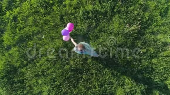 阳光明媚的一天在绿色草坪的背景下头发鲜艳的青少年正在用气球旋转鸟瞰视频的预览图