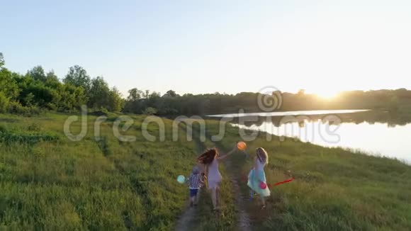 在绿色的草地上孩子们手里拿着彩带和球兴高采烈地奔跑着视频的预览图