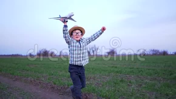 周末快乐孩子拿着玩具飞机沿着绿色的田野奔跑视频的预览图