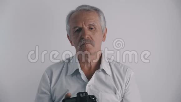 白发苍苍的资深男摄影师用白底照相相机拍照视频的预览图