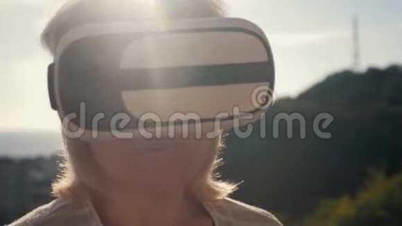 太阳落山时一个戴着虚拟现实眼镜的女孩在房子的屋顶上生命生命概念视频的预览图