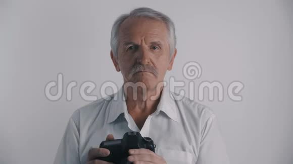 白发苍苍的资深男摄影师用白底照相相机拍照视频的预览图