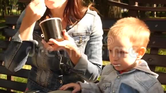 男孩放纵地坐在公园的长凳上孩子脏了在冰淇淋染色衣服妈妈家庭饮食视频的预览图