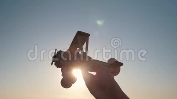 的手拿着一架木飞机对着夕阳视频的预览图