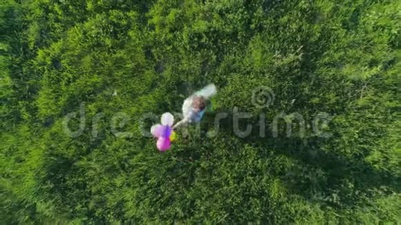 快乐的时刻带着彩色气球的青少年无人驾驶的视野正在草地上旋转视频的预览图