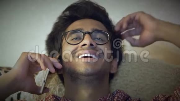 特写镜头戴眼镜的英俊印度男人在沙发上打电话视频的预览图