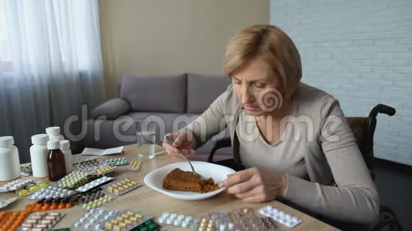 病残妇女在桌上吃甜点吃药康复视频的预览图