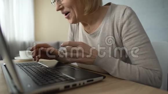 微笑的老年女士在笔记本电脑上打字在约会网站上交流视频的预览图