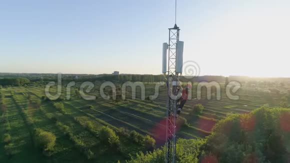 工程师在天线通讯塔上工作在阳光下展示城市景观背景视频的预览图