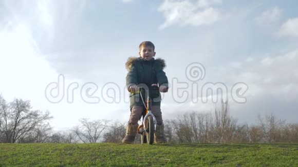 积极的娱乐活动孩子在没有踏板的情况下骑自行车在大自然的绿色滑梯上视频的预览图