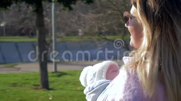 婴儿护理戴太阳镜微笑的女性带着新生儿在街上散步视频的预览图