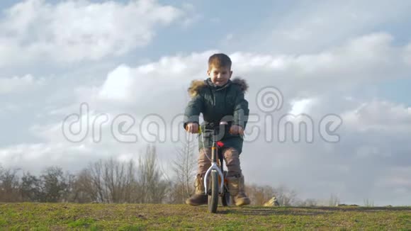 儿童游戏幼儿骑自行车没有脚踏板从户外滑梯在春天视频的预览图