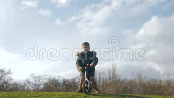 平衡孩子骑自行车没有踏板从绿色滑梯在露天视频的预览图