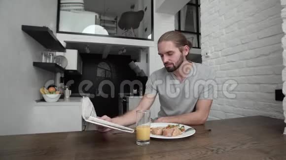 男人在厨房里看报纸和吃早餐视频的预览图