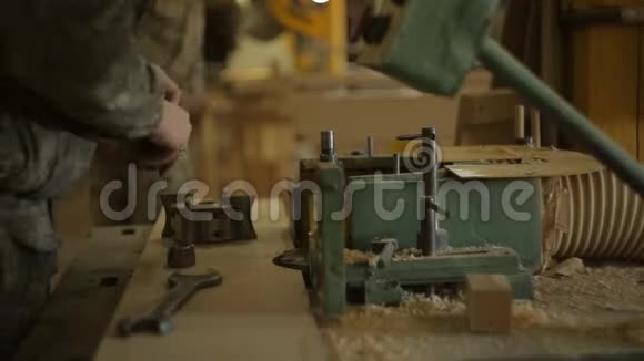 锯木厂的工人在切边机上更换刀具并将机器设置为木材加工特写视频的预览图
