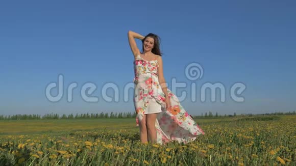 一个微笑的女人站在一个绽放的黄色田野穿着衣服的肖像视频的预览图