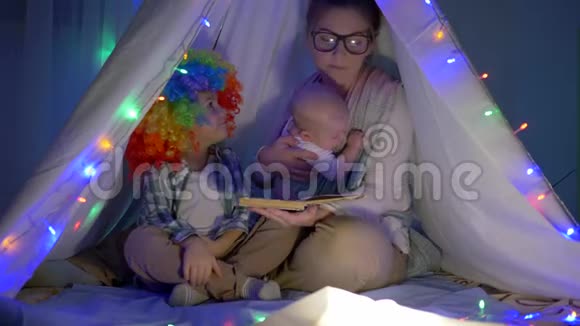 家庭气氛母亲在晚上用花环给孩子们讲一个童话故事视频的预览图