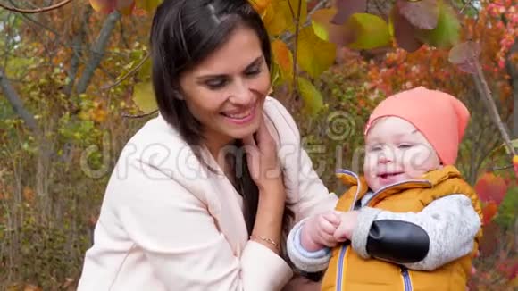 母亲和童年美丽的孩子和母亲在秋天的城市公园的特写镜头中度过了一段美好的户外时光视频的预览图