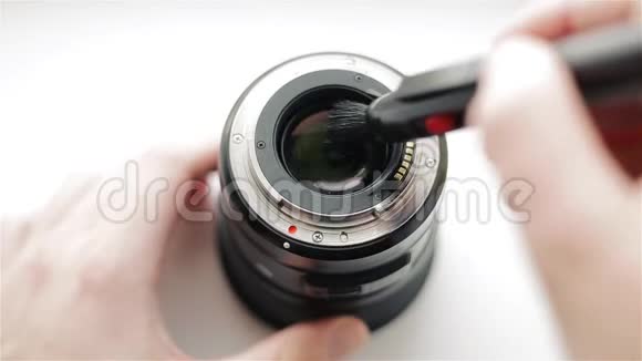 摄影师用一支专业的铅笔把现代镜头的背面从灰尘中清理干净以照顾它视频的预览图