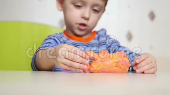 孩子们创造力这孩子用面团塑造一个球可爱的儿童表格从塑料在桌子上视频的预览图