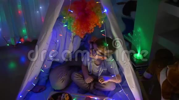 孩子们的娱乐活动可爱的带着小丑的蹒跚学步的孩子在晚上装饰着花环的帐篷里玩得很开心视频的预览图