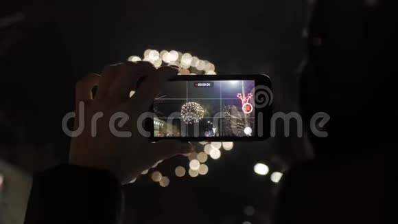 一个女人在智能手机上燃放烟花用智能手机制作美丽烟花的视频供庆祝视频的预览图