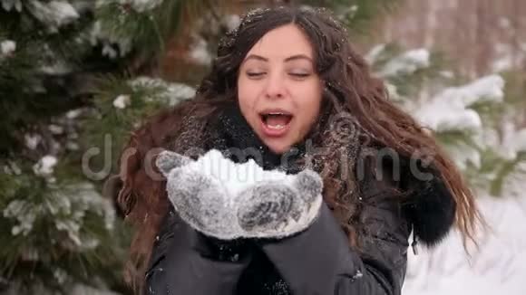 在冬天的公园里怀孕的女孩吹着雪视频的预览图