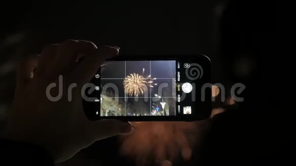 一个女人在智能手机上燃放烟花用智能手机制作美丽烟花的视频供庆祝视频的预览图